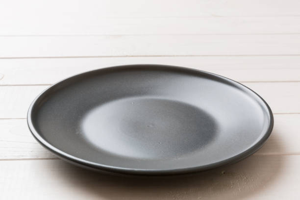 istock Perspective view of empty black plate on wooden background. Empty space for your design 1396840318
