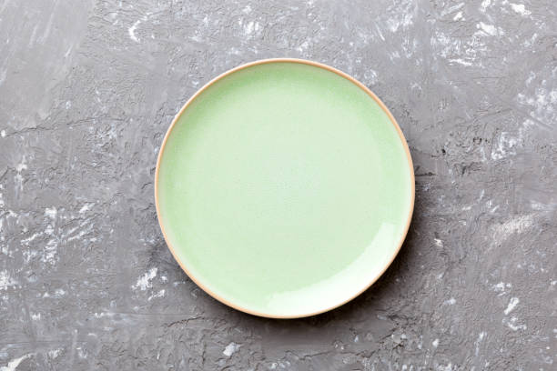 istock Top view of empty green plate on cement background. Empty space for your design 1396840430