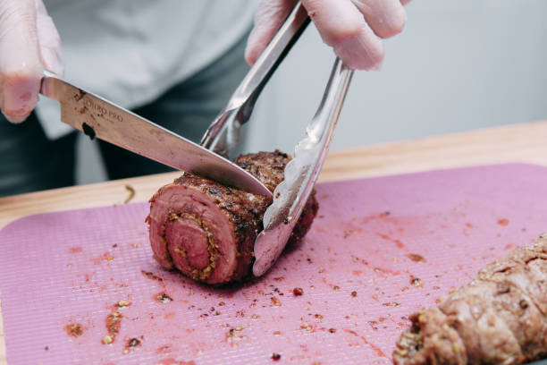 kochen von fleischbrötchen im kochkurs. rinderrolle mit gewürzen. der prozess des schneidens einer rolle, nahaufnahme. - animal bone chop close up color image stock-fotos und bilder