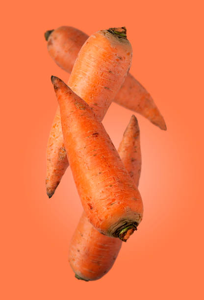 istock ripe large carrots flying on an orange background, creative photo 1396840782