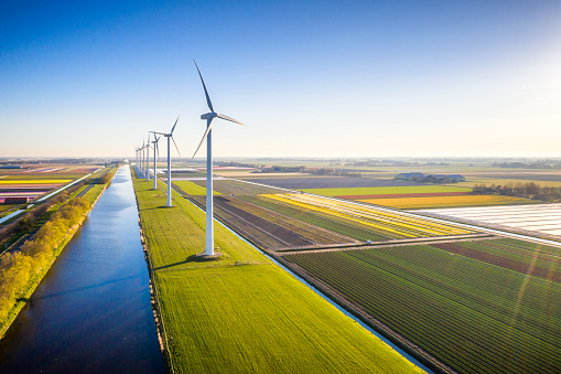 Aerial view of wind turbines near a canal in Holland in a sunny day with a clear sky