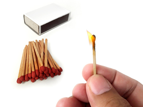 Male hands hold a match with a flame and Box of matches. isolated on a white background