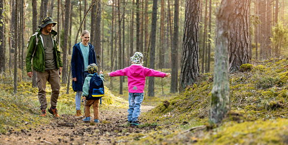 active young family with two children spend time together on a walk in forest. copy space
