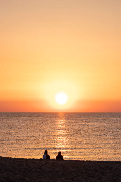 istock young couple watching the sunrise on the beach 1396849258