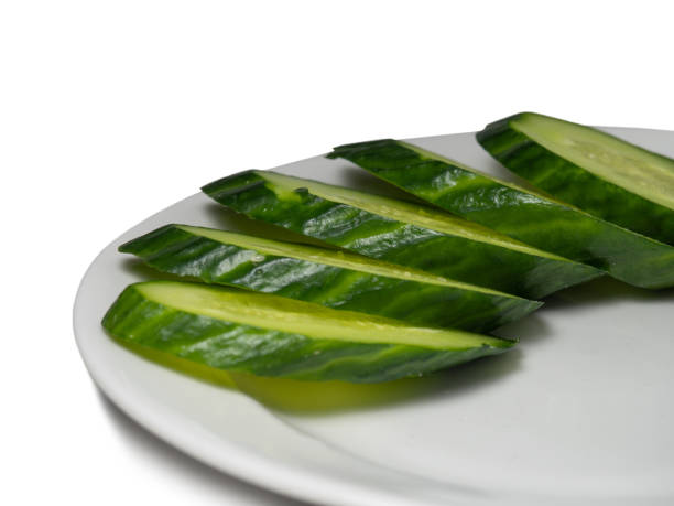 istock A smooth, medium-sized cucumber on a white plate. Cucumber on a yellow background. Sliced 