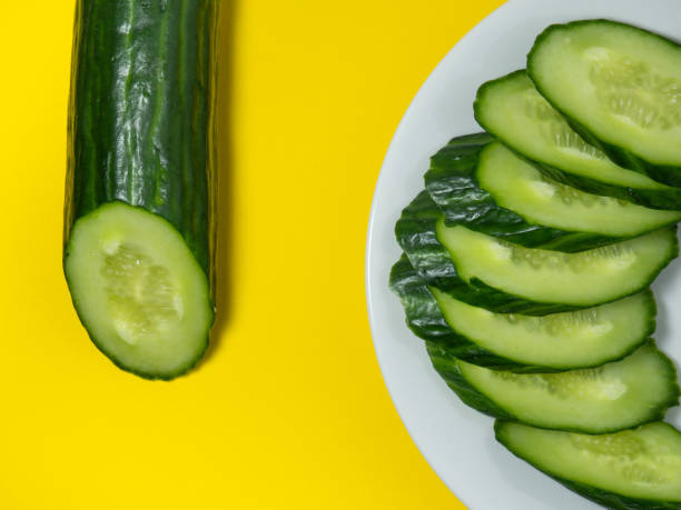 istock A smooth, medium-sized cucumber on a plate, sliced. Cucumber on a yellow background. 1396853273