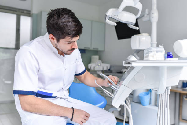 istock Modern Male Dentist Preparing Equipment For Next Patient 1396854614