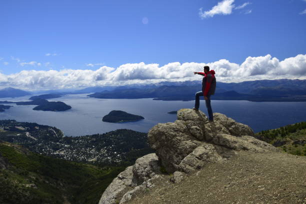 un hombre en una roca observa el paisaje en san carlos de bariloche, vista del lago y la ciudad de bariloche - bariloche argentina summer landscapes fotografías e imágenes de stock