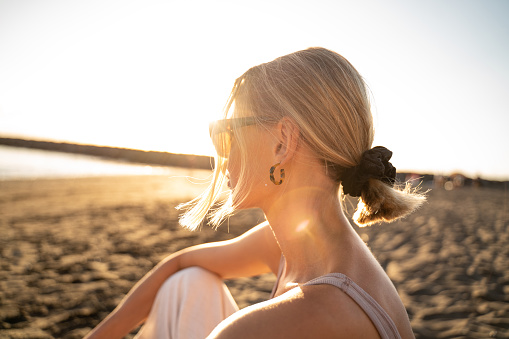 Beautiful blonde woman portrait in sunset on the beach. Profile. Relax. Medittation.
