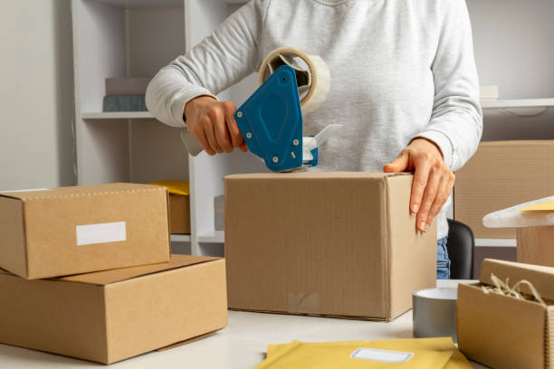 istock A warehouse worker seals a box with goods for delivery by mail with a dispenser. 1396859430