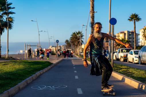 senior fit man with beard skateboard on the street in La Serena
