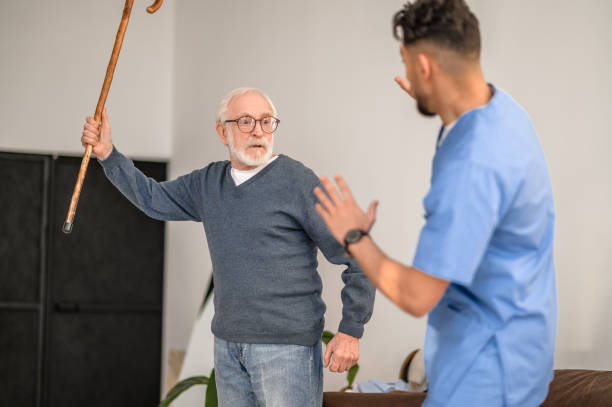 istock Exasperated pensioner threatening his caretaker with his cane 1396861231