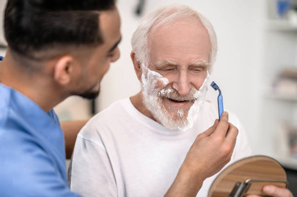 istock Caring volunteer giving a pleased old man a shave 1396861353