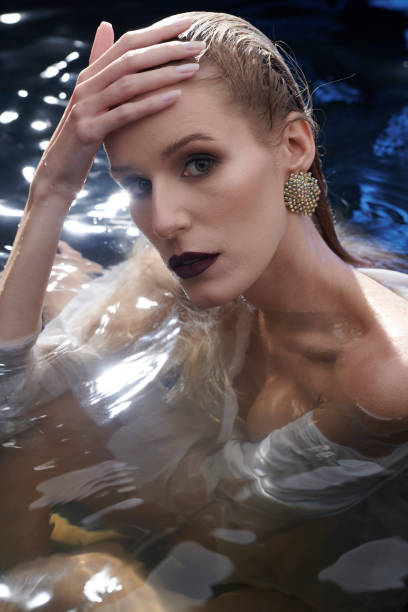 istock Underwater meditation. Seductive woman emerging from clear water. Reflecting lights 1396863496