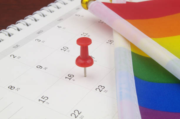 istock Red push pin on calendar page and LGBT flags. 1396864559