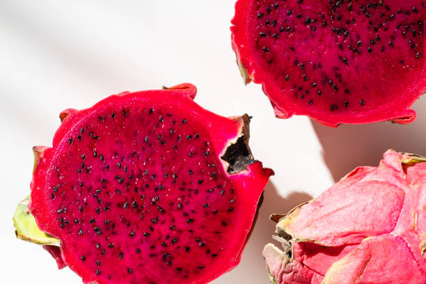istock Juicy ripe pitahaya whole and scattered on a white background. View from above. Hard light, shadow from a palm tree. Thai exotic fruits. 1396865106