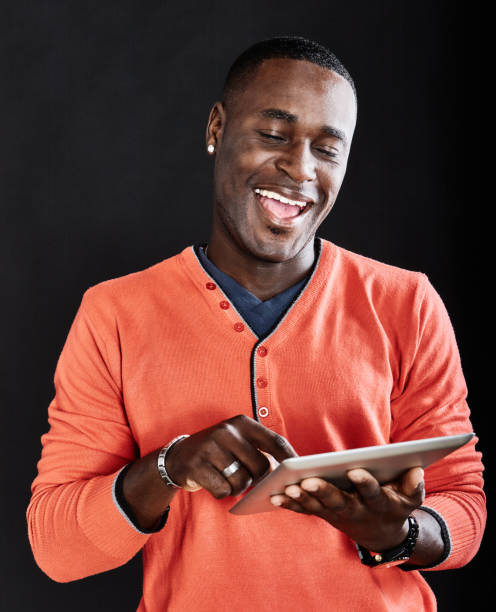 istock Handsome young man smiles and laughs as he stands using a digital tablet computer 1396865867