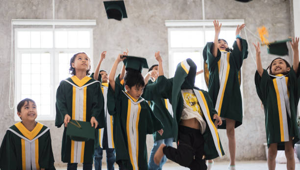 Childhood students and friends with graduation gown stock photo