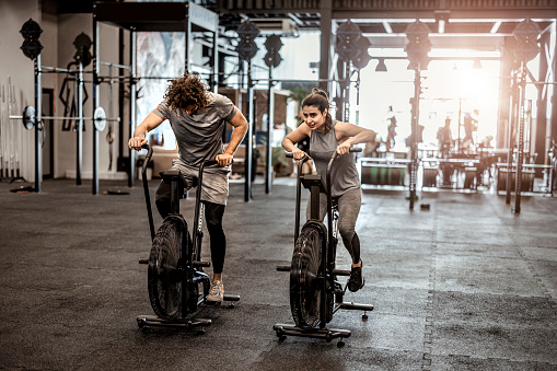 gym man an woman doing intense cardio training on exercise bike
