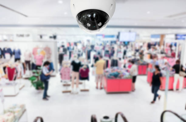 istock Modern public CCTV camera with blur interior shopping mall background. Recording cameras for monitoring all day and night. Concept of surveillance and monitoring with copy space. 1396871105