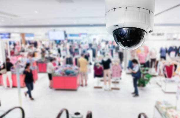 istock Modern public CCTV camera with blur interior shopping mall background. Recording cameras for monitoring all day and night. Concept of surveillance and monitoring with copy space. 1396871106