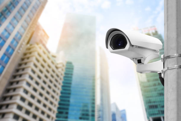 istock Modern public CCTV camera on wall with blur building background. Recording cameras for monitoring all day and night. Concept of surveillance and monitoring with copy space. 1396871108
