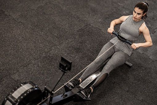 Woman training on row machine in gym