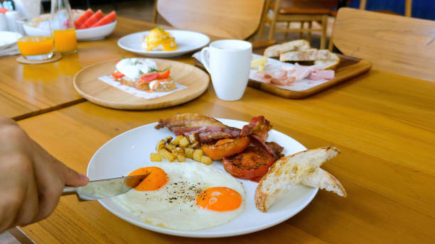 istock Male hand with table knife cut fried egg with liquid yolk inside in restaurant 1396872889