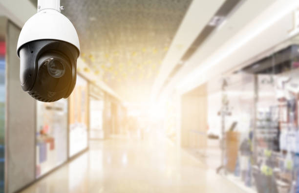 istock Modern public CCTV camera with blur interior shopping mall background. Recording cameras for monitoring all day and night. Concept of surveillance and monitoring with copy space. 1396873119