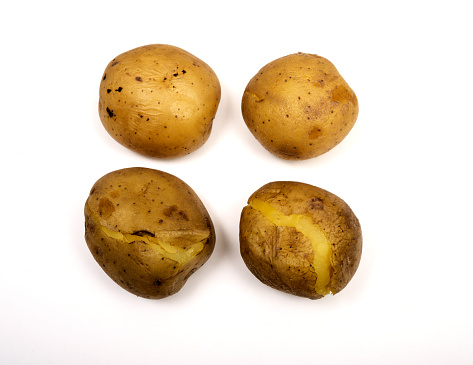 four boiled potatoes in their skins on a white background