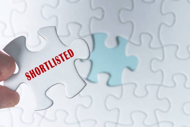 istock Hand holding piece of jigsaw puzzle with word Shortlisted. 1396880941