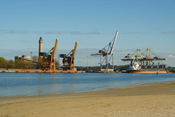 промышленная зона на побережье. большие краны на заднем плане. порт - barge beach large blue стоковые фото и изображения