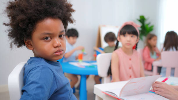 istock African American sitting in the kindergarten classroom during drawing or paining class. Feeling angry, boring and upset. Education and learning concept. Lifestyle in school. Lazy to study 1396882702