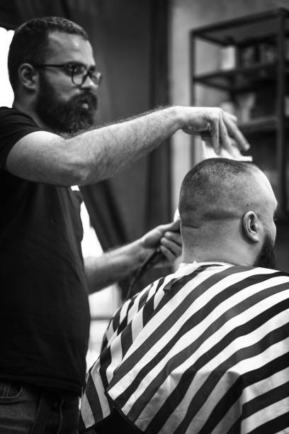 istock Hipster barber styling a customer in his barber shop 1396884169
