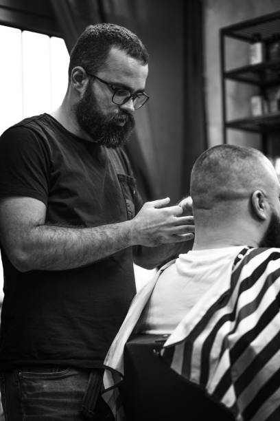 istock Young attractive barber with a beard cutting hair 1396884222