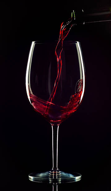 Red wine being poured into a glass on a black background