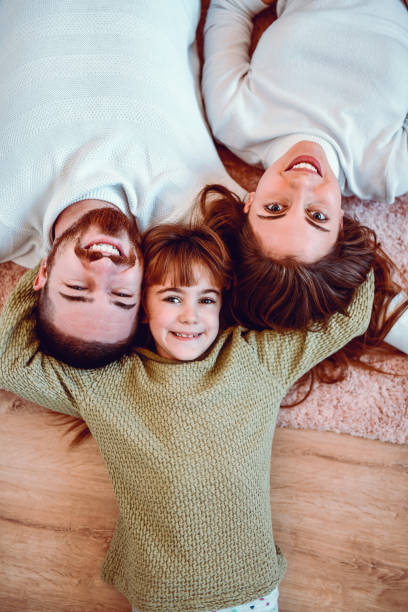 glückliche familie, die zeit miteinander verbringt, wenn sie zu hause auf dem boden liegt - carpet floor lying down people stock-fotos und bilder