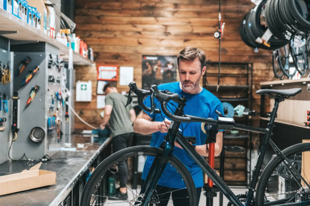 mężczyzna sprawdzający nowy rower w warsztacie - vehicle part warehouse storage room repairing zdjęcia i obrazy z banku zdjęć