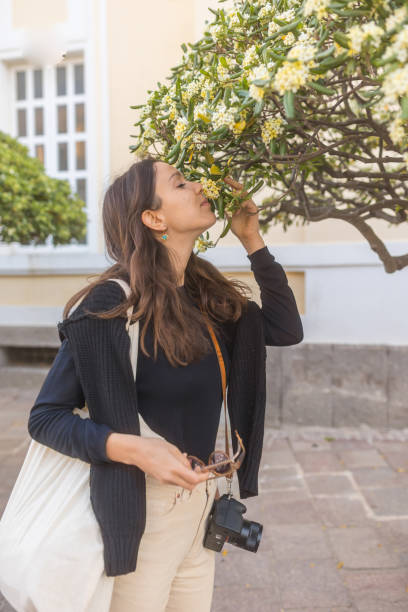 Young woman stops to smell citrus blossoms