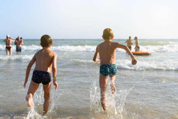 Two children on their backs running into the sea water