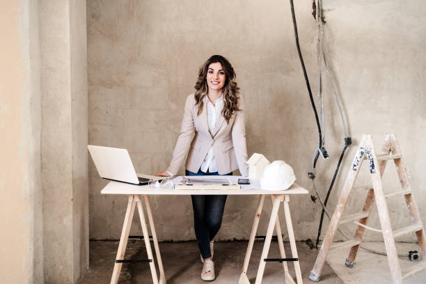 istock professional confident architect woman in construction site working on blueprints. Home renovation 1396896488