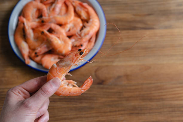 istock Hand holding a shrimp with full plate on wooden background. Copy space. 1396897504