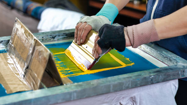 istock male hands  with a squeegee. silkscreen printing. serigraphy production selective focus photo. printing images on clothes by silk screen method in a design studio 1396899458