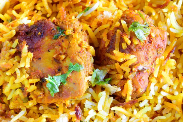 Photo of Closeup of dum baked chicken tikka biryani prepared with juicy, marinated and barbecued chicken pieces and aromatic basmati long grained rice.