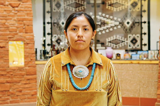 A portrait of a Native American Navajo woman standing.