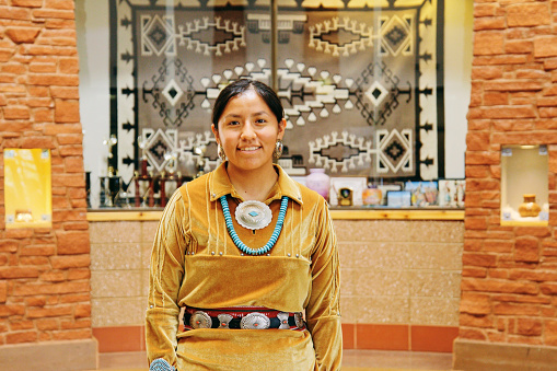 A portrait of a Native American Navajo woman standing.