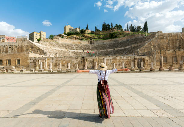 Amman, jordan - young girl with hat standing with open arms looking the Roman Theater one of the most important tourist attractions in Amman, Jordan. stock photo