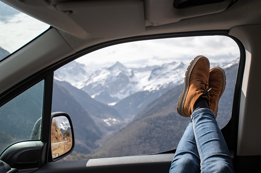 woman legs resting on the window of a van with views of snowy mountains in the pyrenees