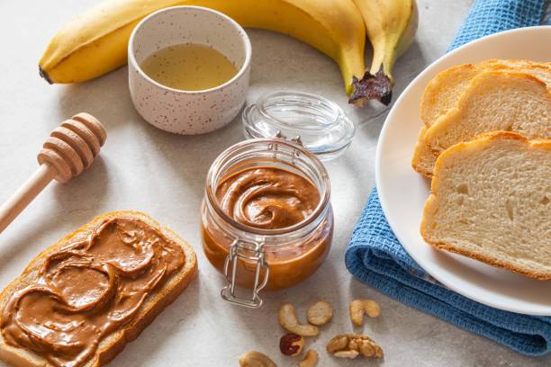 istock Nut butter toast with bananas and honey on light table. Walnut, hazelnut and cashew nut spread in glass jar. Homemade breakfast sandwich. Healthy food concept. 1396908865