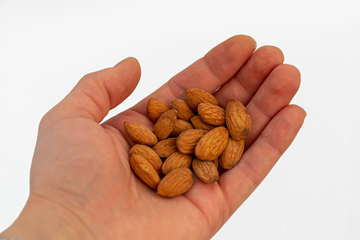 Young man hands holding almonds on background